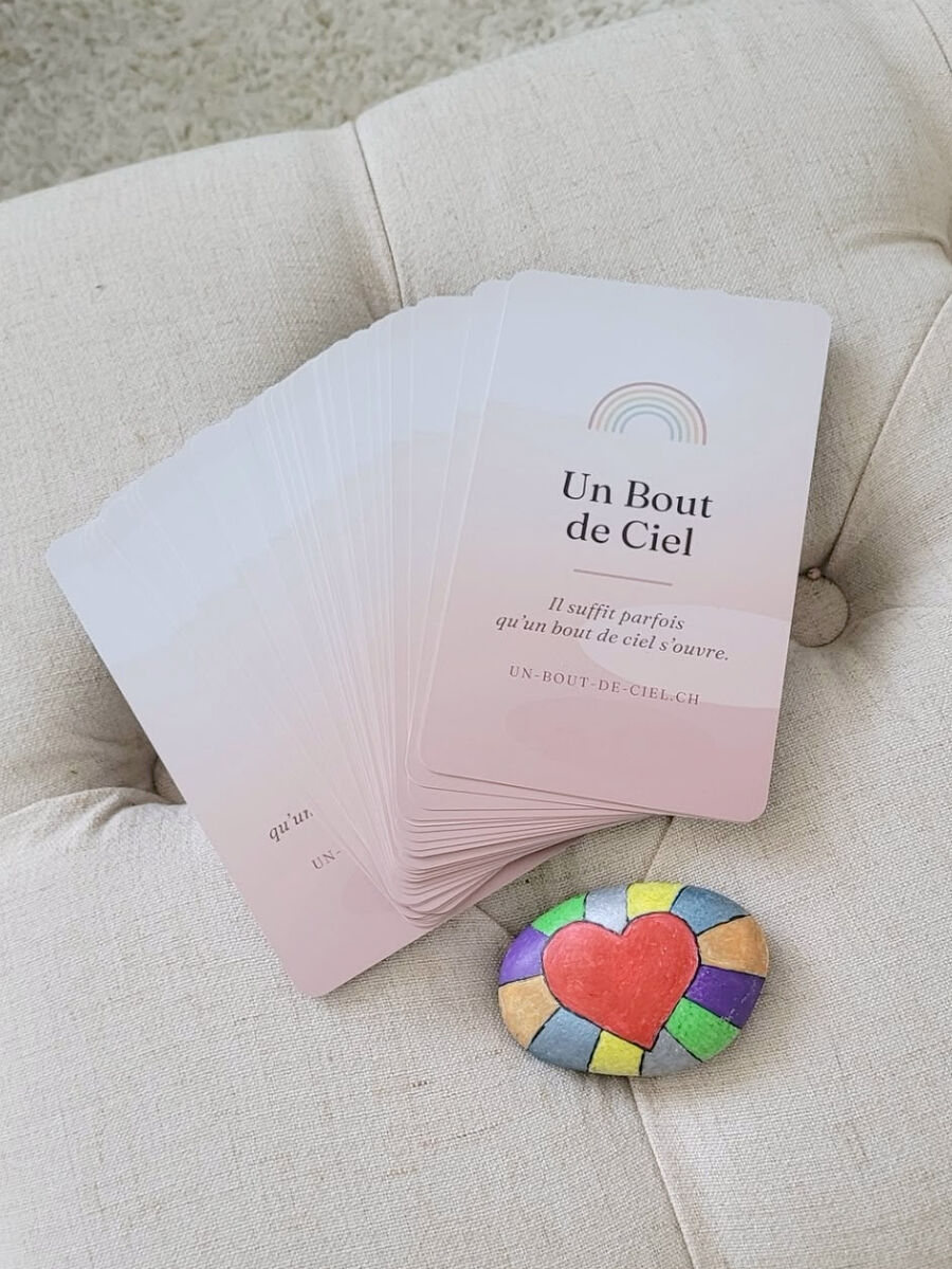 Les cartes Un Bout de Ciel déployées sur le pouf, à côté d’un galet peint d’un cœur