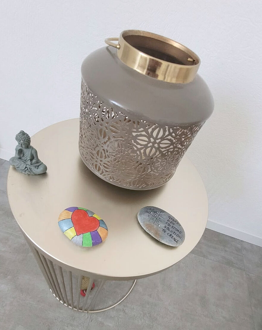 Une lanterne dorée, un petit bouddha et des galets peints sur une table d’appoint