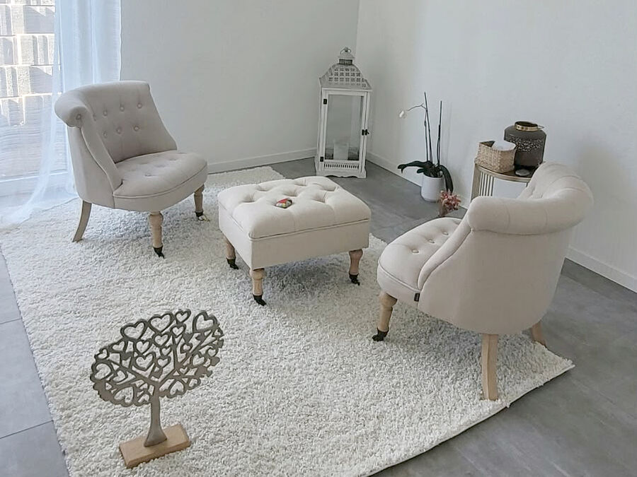 Le cabinet Un Bout de Ciel à Saint-Aubin-Sauges : deux fauteuils beiges face à face, un pouf capitonné et un tapis blanc